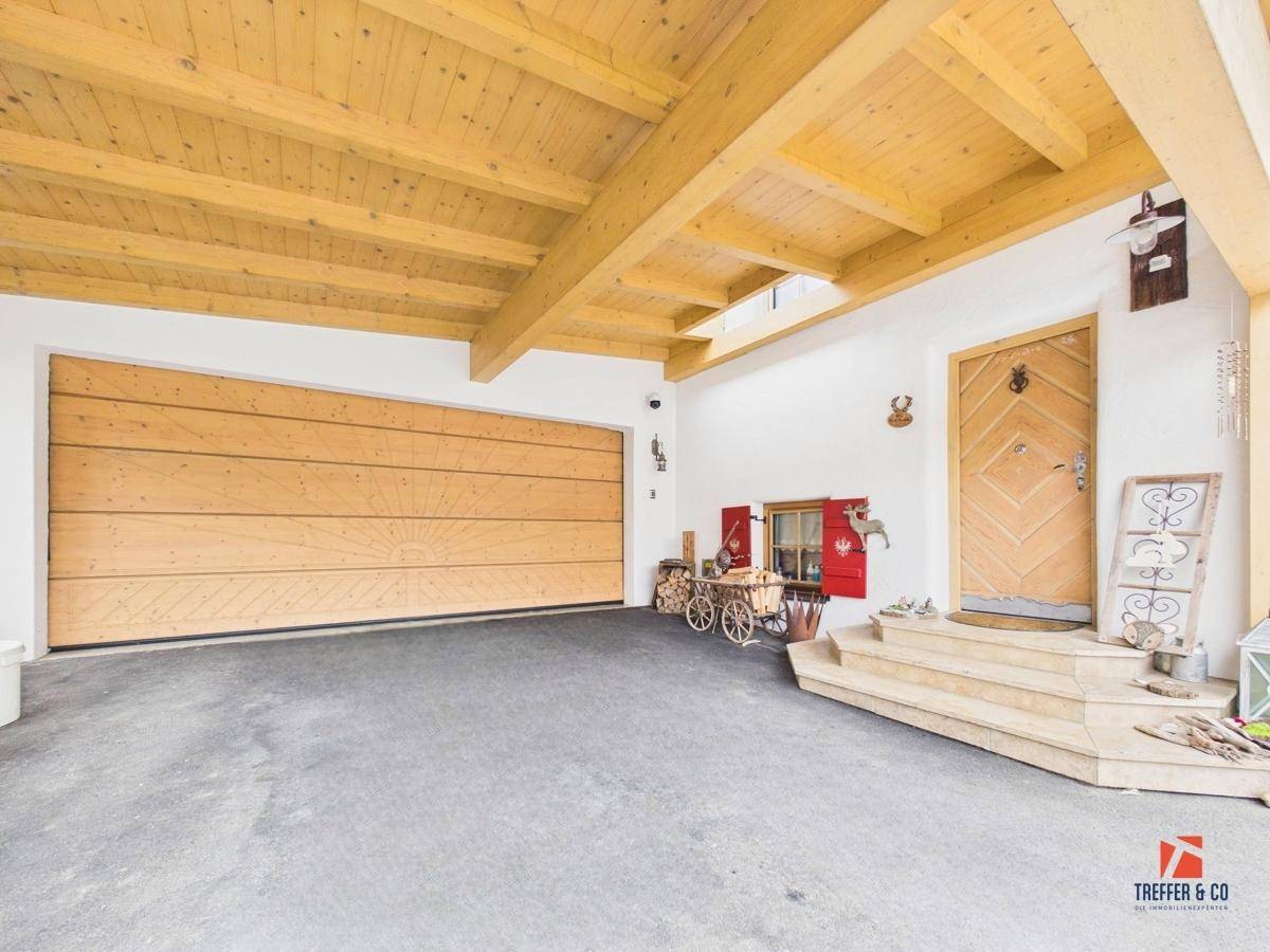 Traditioneller Eingangsbereich mit Holzdecke, großer Holzgaragentür und charmanten alpinen Details.