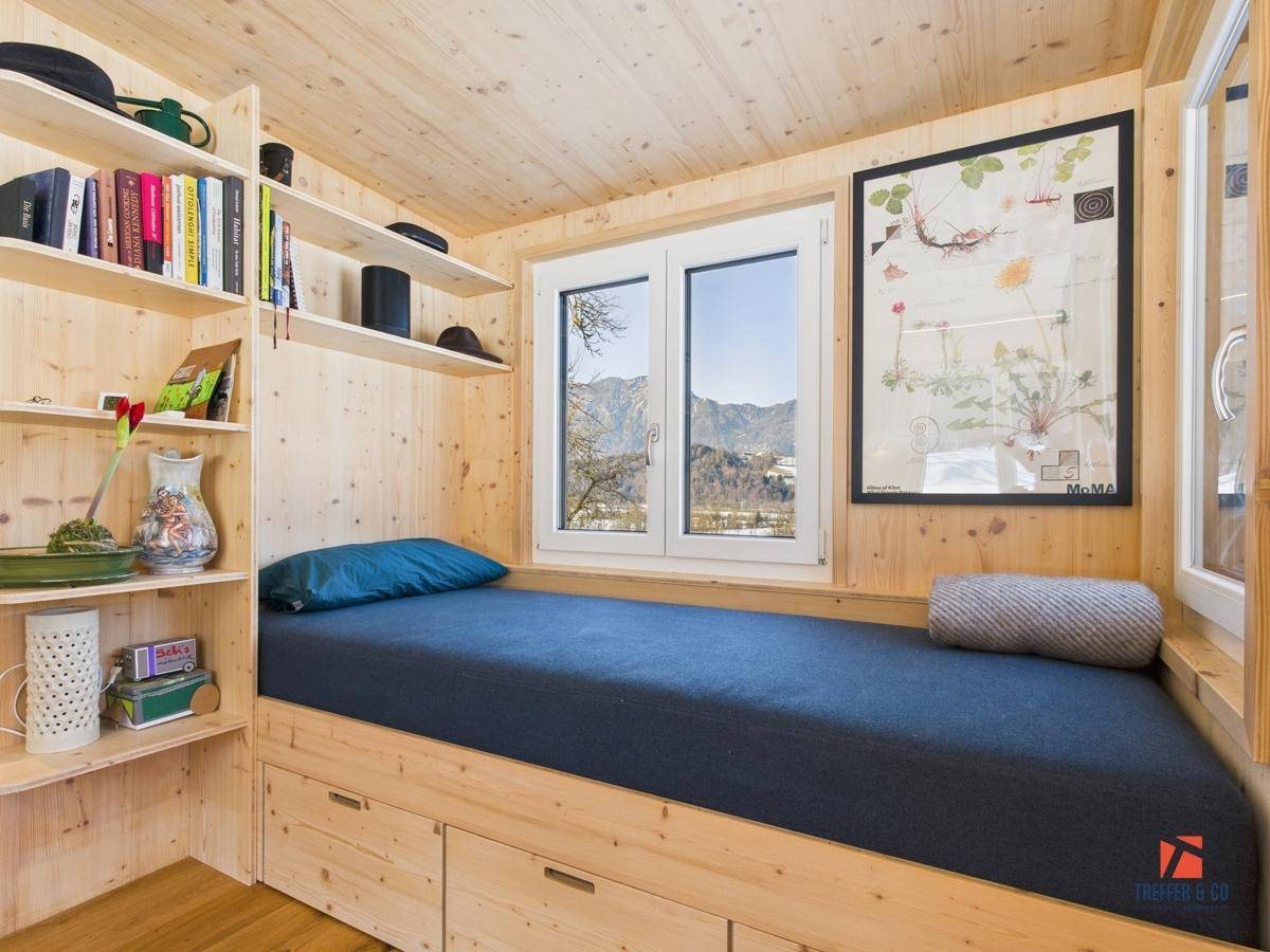 Gemütliches Schlafzimmer mit Holzwänden, integriertem Bett und Regalen sowie Bergblick.