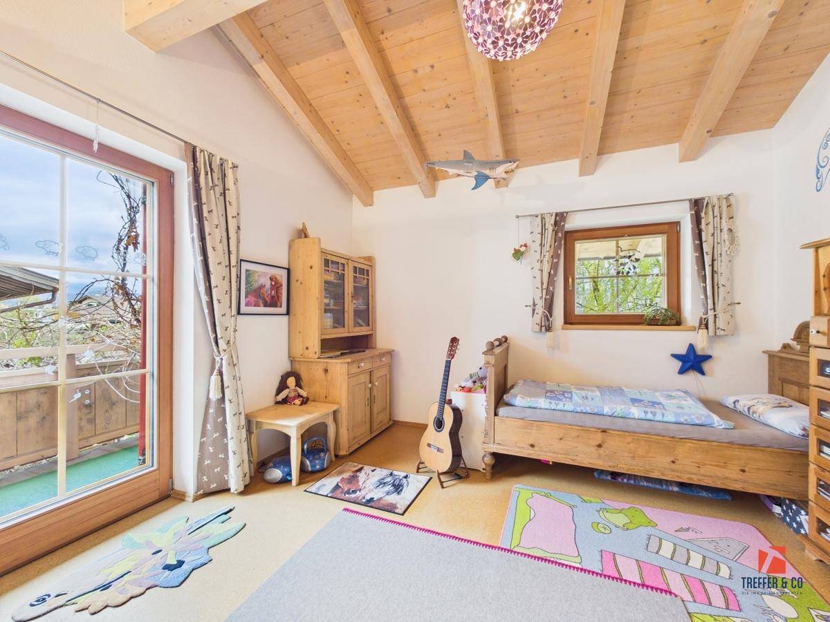 Helles Kinderzimmer mit Holzbalkendecke, Einzelbett und Balkonzugang, ideal für junge Bewohner.