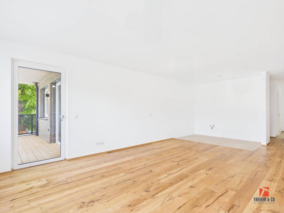 Heller Wohnbereich mit Holzboden und Zugang zu einem Balkon.