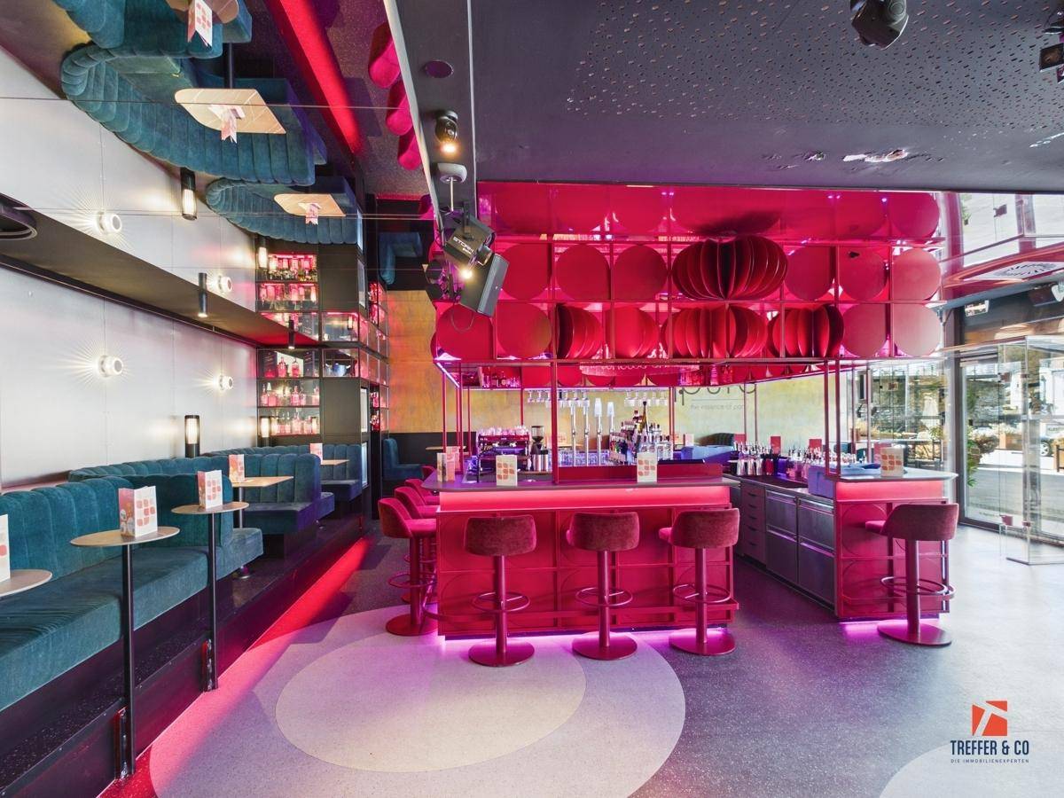 Moderner Barbereich mit leuchtend pinker Beleuchtung, Barhockern und einer gut bestückten Theke.