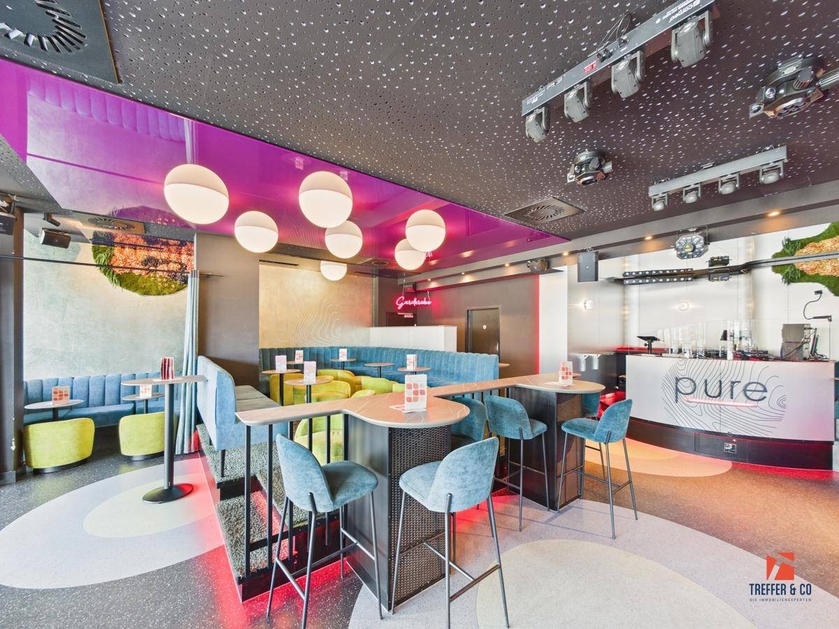 Moderner Loungebereich mit vielfältigen Sitzgelegenheiten, einer Rezeption und großen Fenstern.