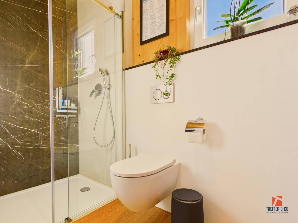 Modernes Badezimmer mit begehbarer Dusche, wandhängendem WC und Marmorfliesen.