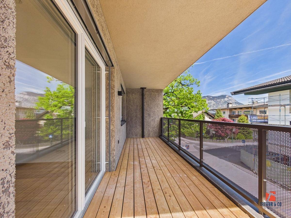 Langer Balkon mit Holzdielen, modernem Geländer und Blick auf die Umgebung.