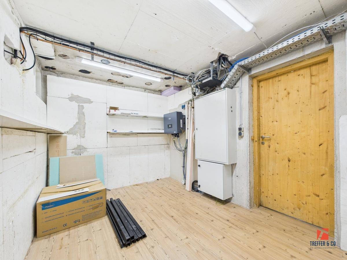 Kellerraum mit Holztür, elektrischen Installationen und unfertigen Wänden.