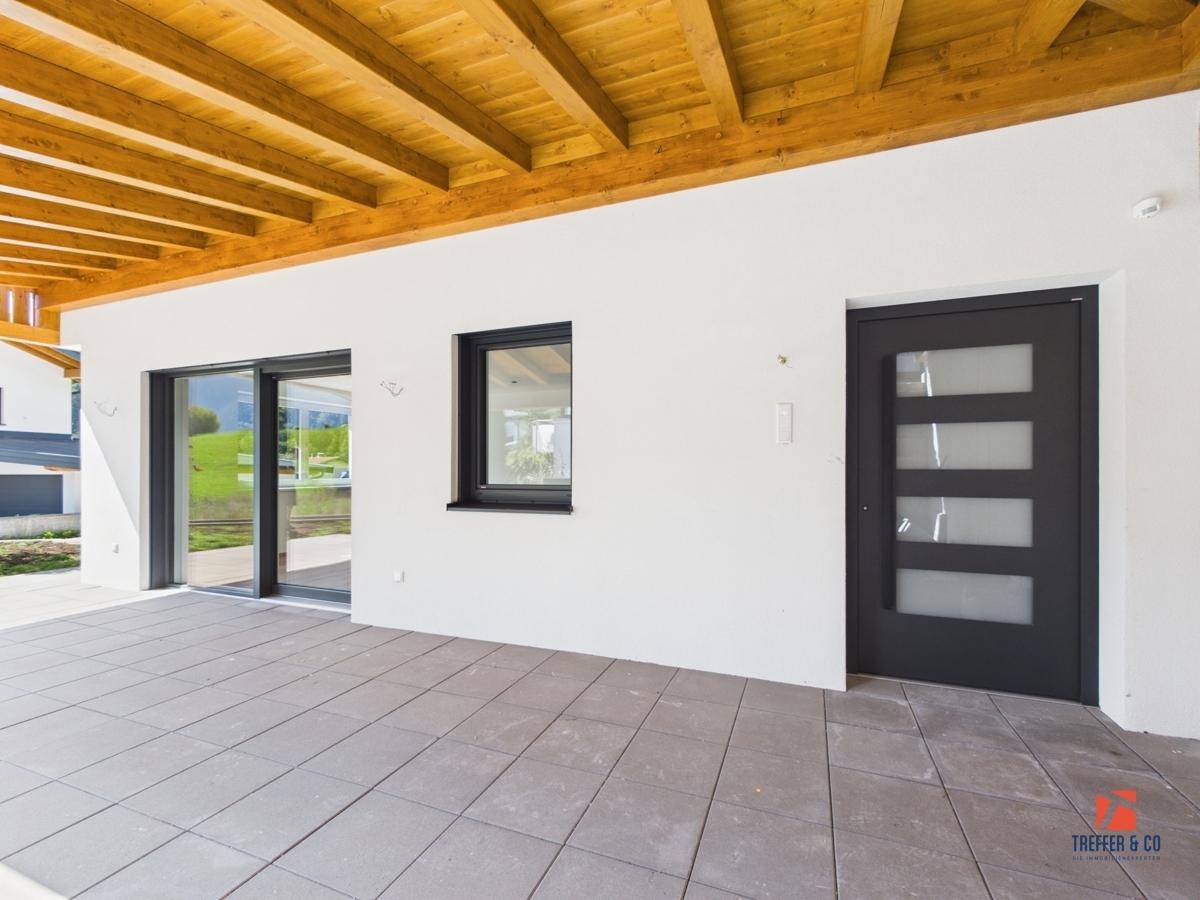 Überdachter Terrassenbereich mit Zugang zum Haus und moderner Eingangstür.
