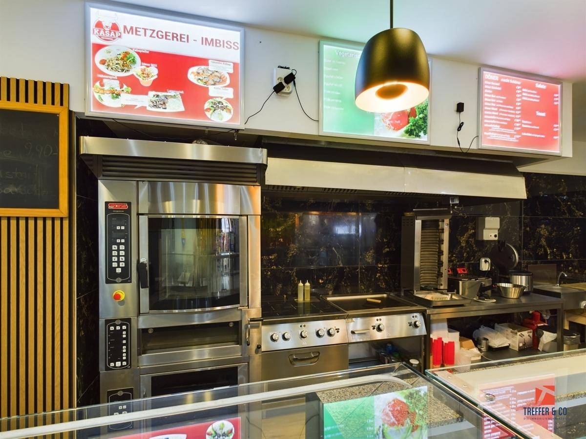 Professionelle Küche mit großem Ofen, Kochfeld und Dunstabzugshaube für Gastronomiebetriebe.