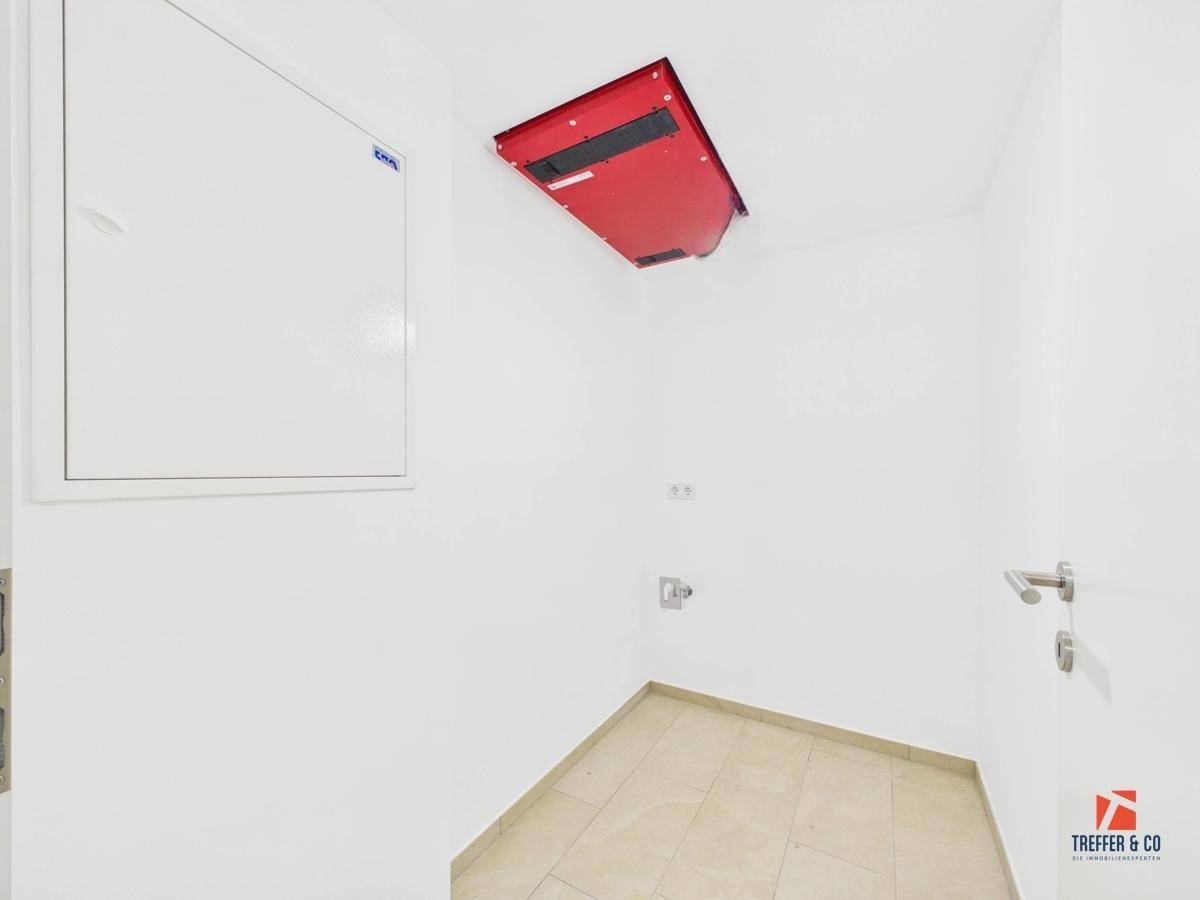 Praktischer Hauswirtschaftsraum mit Fliesenboden und Zugang zum Dachboden.