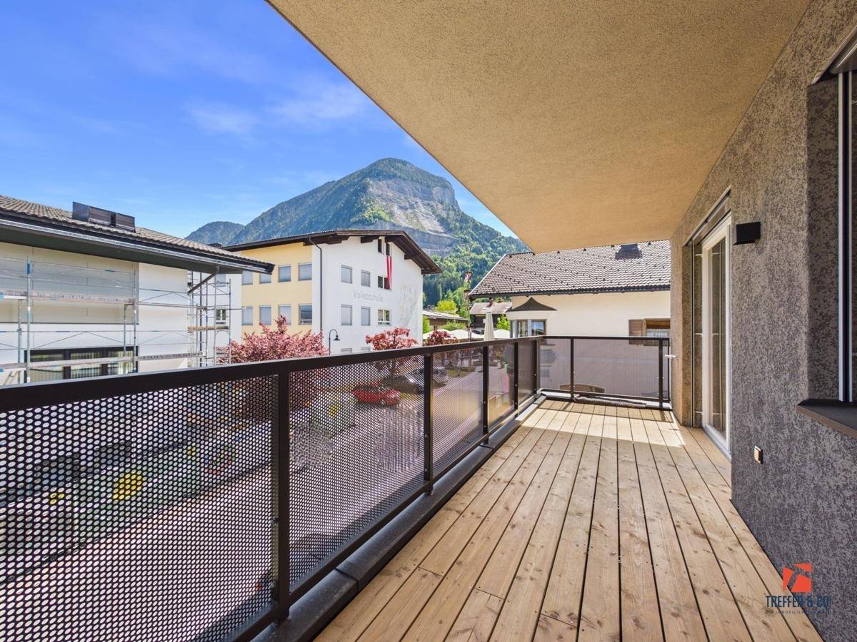 Geräumiger Balkon mit Holzboden, Metallgeländer und herrlichem Bergblick.