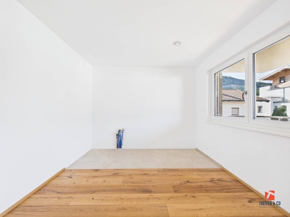 Heller Küchenbereich mit Holzboden, Fliesen und Fensterblick auf die Umgebung.