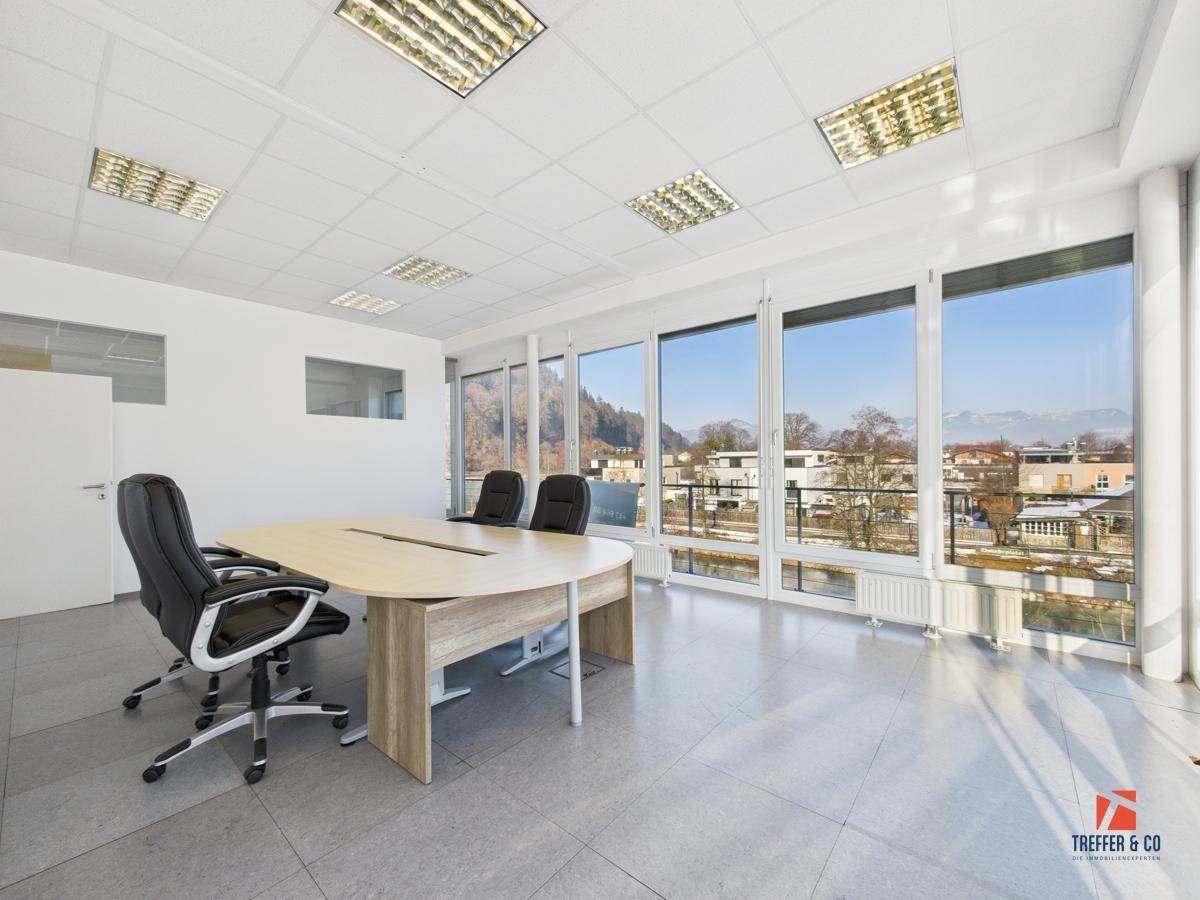 Großer Besprechungsraum mit ovalem Tisch, Bürostühlen und Panoramablick auf die umliegende Berglandschaft.