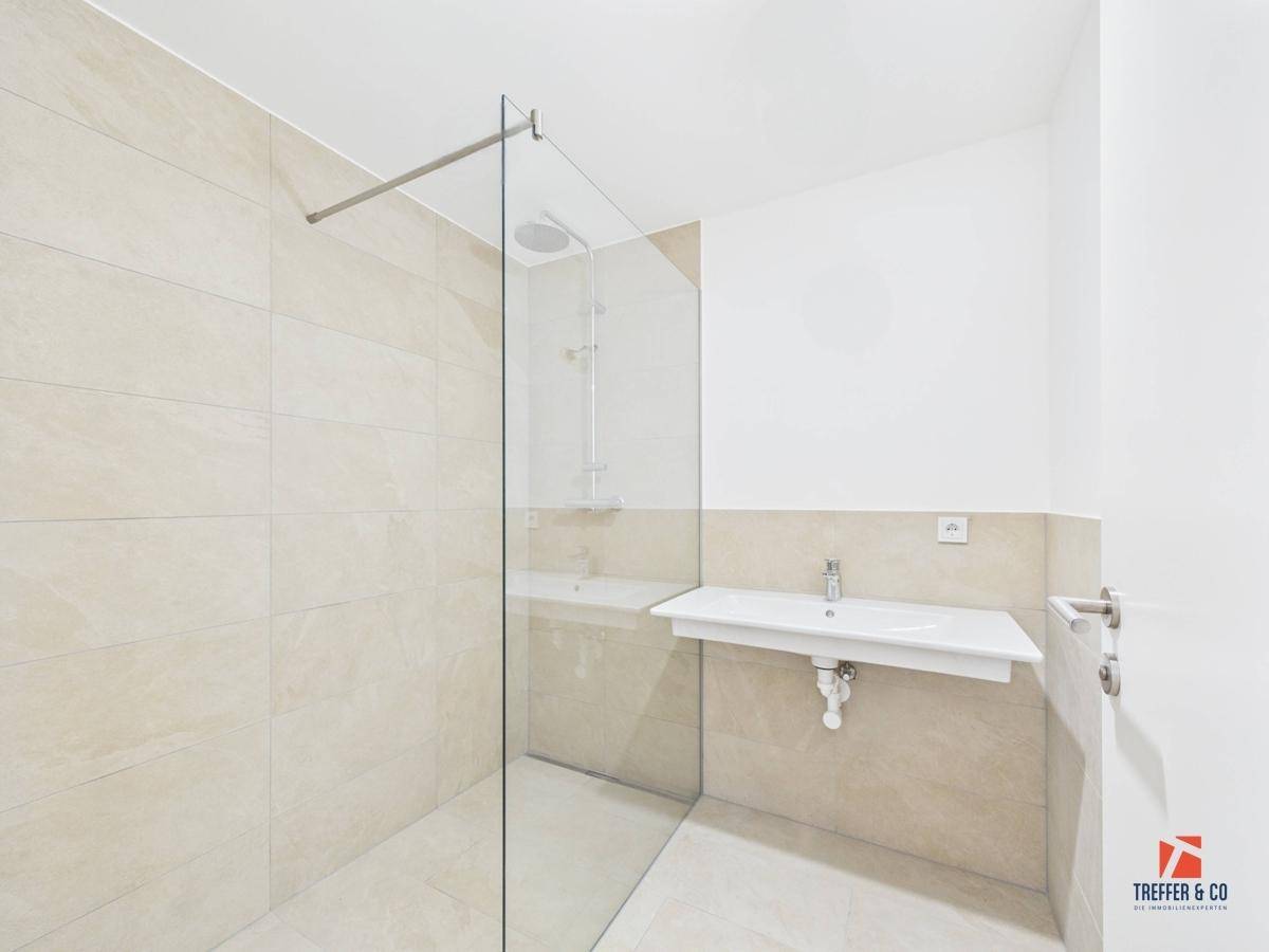 Modernes Badezimmer mit begehbarer Dusche, Wandfliesen und einem einzelnen Waschbecken.