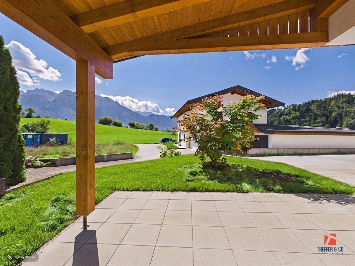 Überdachte Terrasse mit Fliesenboden, Holzbalkendecke und weitem Blick auf die Berge.