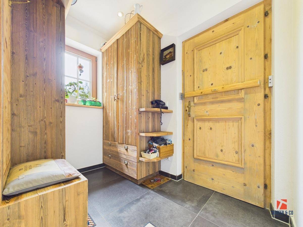 Eingangsbereich mit Holztür, rustikalen Holzschränken und Fliesenboden im Landhausstil.