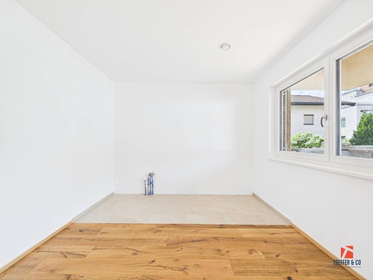 Leerer Raum mit Holzboden und Fliesenbereich, vorbereitet für eine mögliche Nutzung.