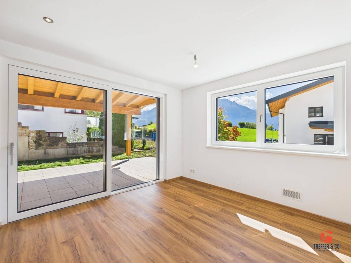 Helles Zimmer mit Laminatboden, Zugang zur Terrasse und weitem Blick auf die Berge.