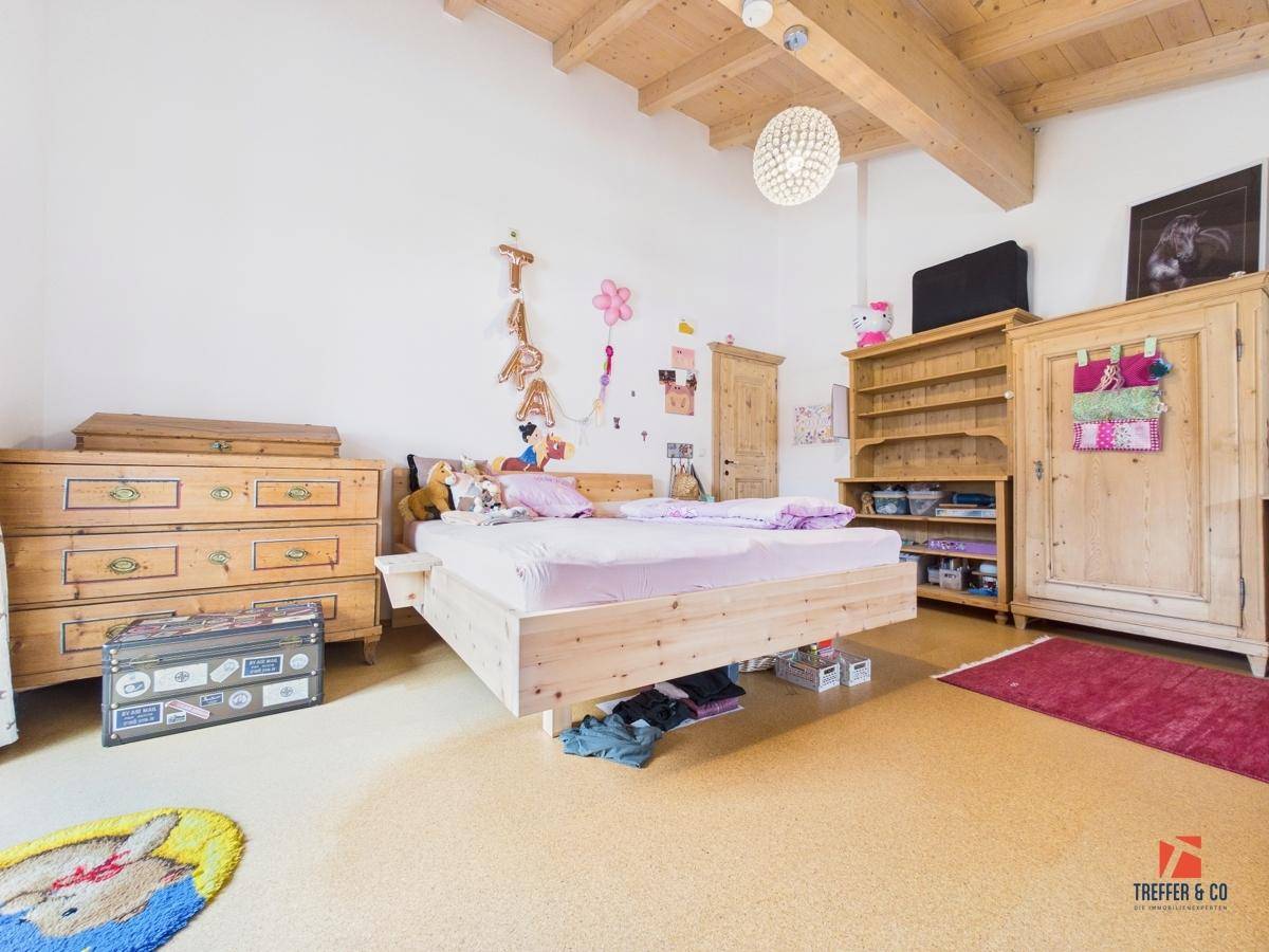 Kinderzimmer mit Holzbalkendecke, Holzbett und traditionellen Holzmöbeln, gemütlich eingerichtet.