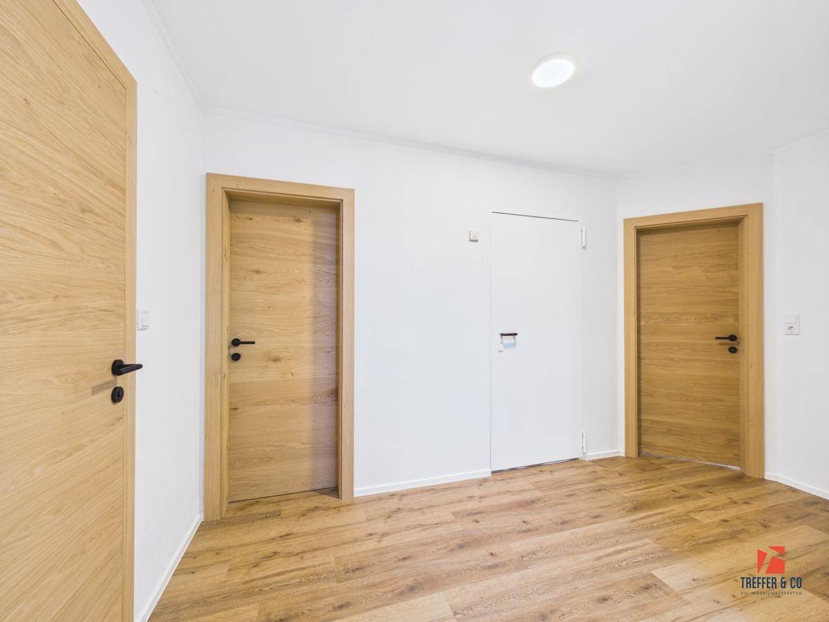 Heller Flur mit Holzboden und mehreren Türen, der zu verschiedenen Räumen führt.