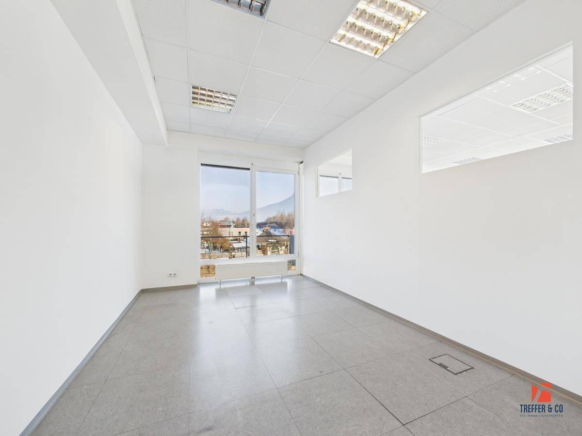 Leeres Büro mit großen Fenstern, die viel Tageslicht hereinlassen, und einem praktischen Fliesenboden.