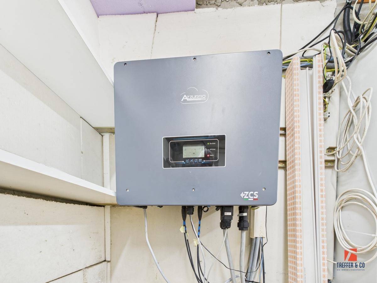 Detailansicht eines Wechselrichters für die Photovoltaikanlage im Technikraum.
