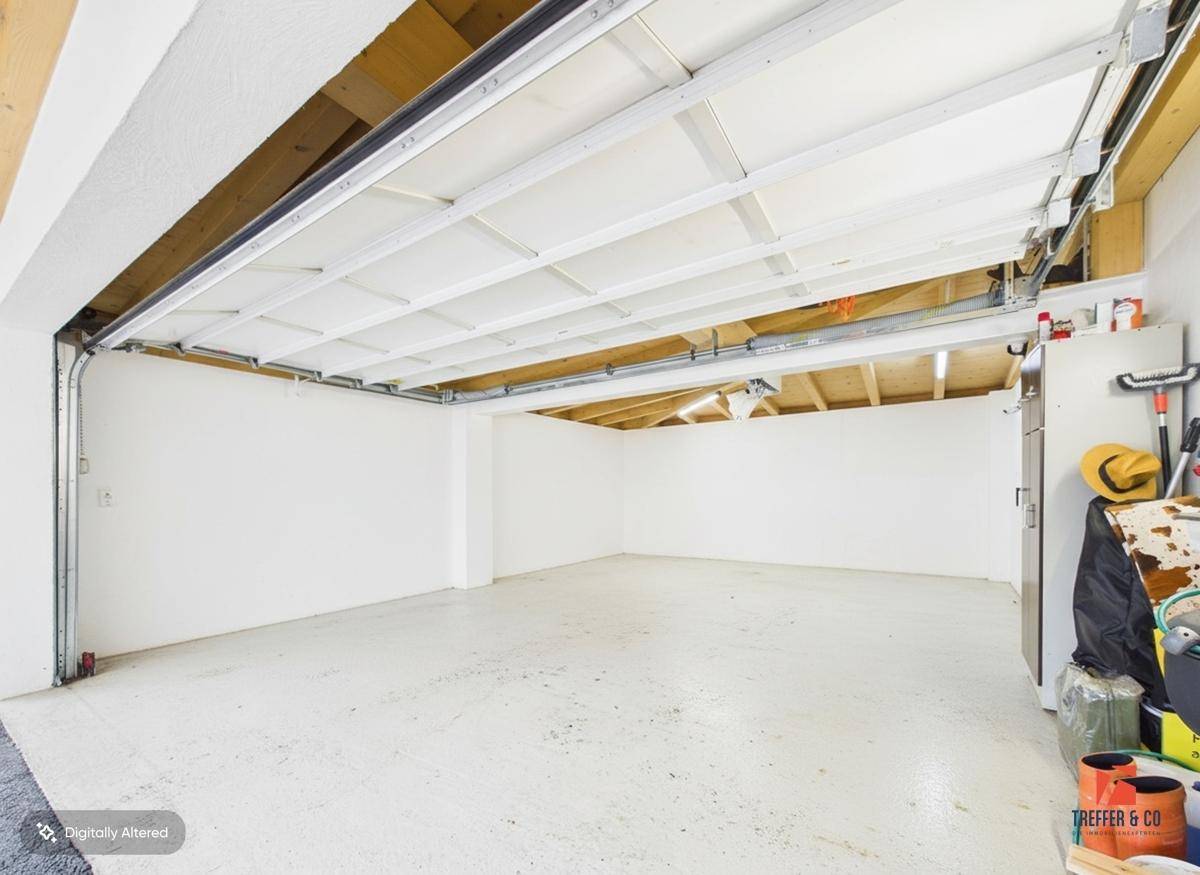 Geräumige, leere Garage mit weiß gestrichenen Wänden und einem hellen, funktionalen Boden.