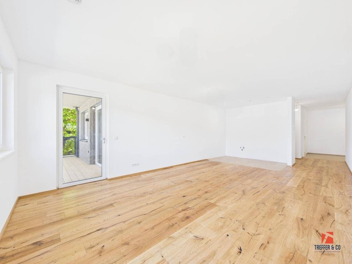 Heller, leerer Raum mit Holzboden und direktem Zugang zu einem Außenbereich.