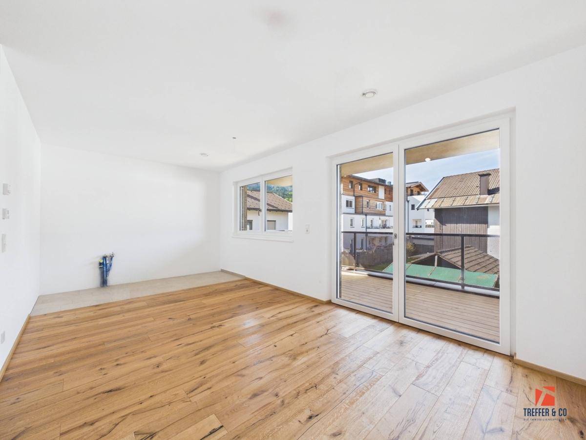 Geräumiges Wohnzimmer mit Holzboden und direktem Zugang zum Balkon.