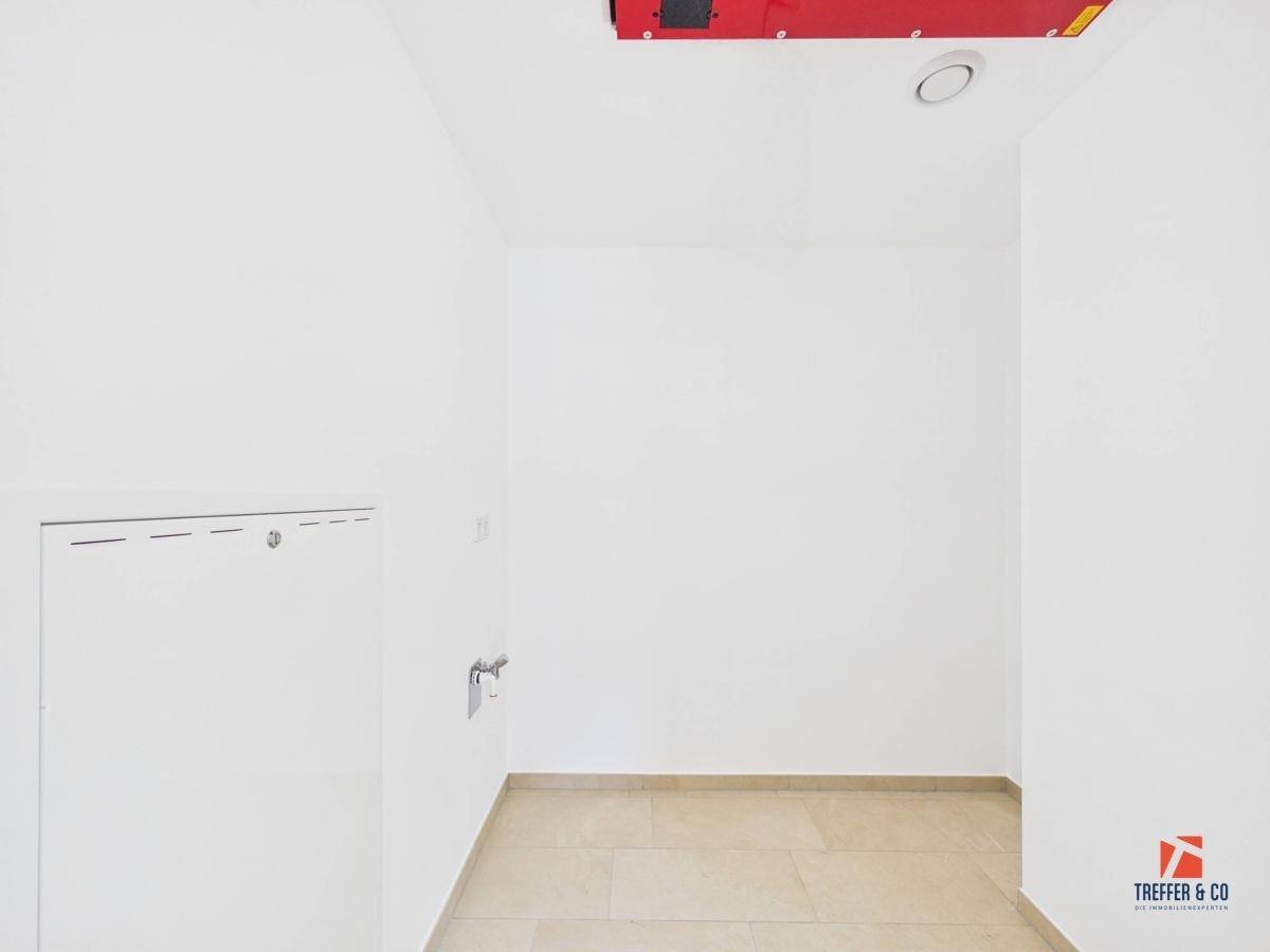 Kleiner Hauswirtschaftsraum mit Fliesenboden und Anschlüssen für Waschmaschine oder Trockner.