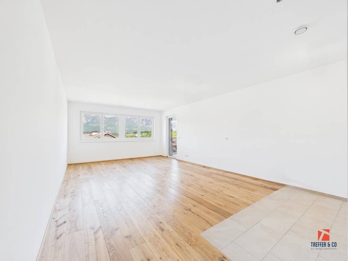 Geräumiger, leerer Raum mit Holzboden, Fliesenbereich und Zugang zu einem Balkon mit Bergblick.