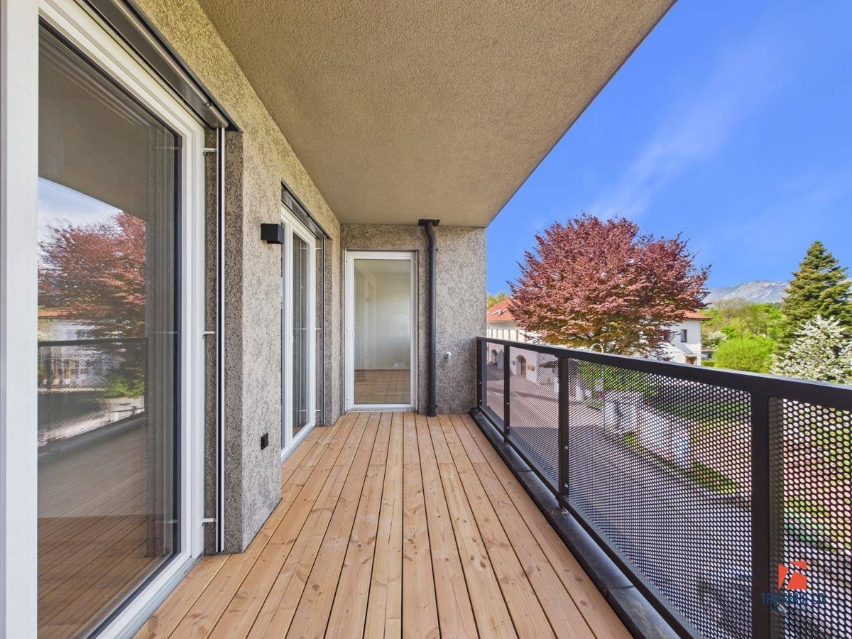 Geräumiger Balkon mit Holzboden und Metallgeländer, bietet einen weiten Blick.