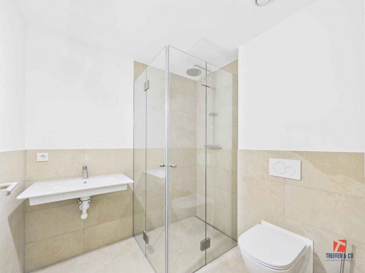 Helles Badezimmer mit Duschkabine, Waschbecken und Wand-WC, in modernen Beigetönen gehalten.
