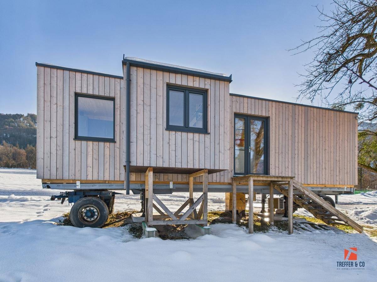 Eingangsbereich des Tiny Houses mit Holztreppe und sonniger Winterlandschaft, umgeben von Natur.