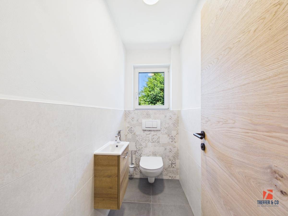 Helles Gäste-WC mit modernem Waschbecken, Toilette und Fenster.