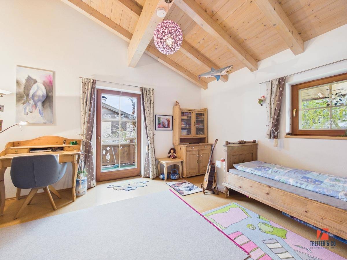 Kinderzimmer mit Holzbalkendecke, Einzelbett und Schreibtisch, mit Balkonzugang und viel Tageslicht.