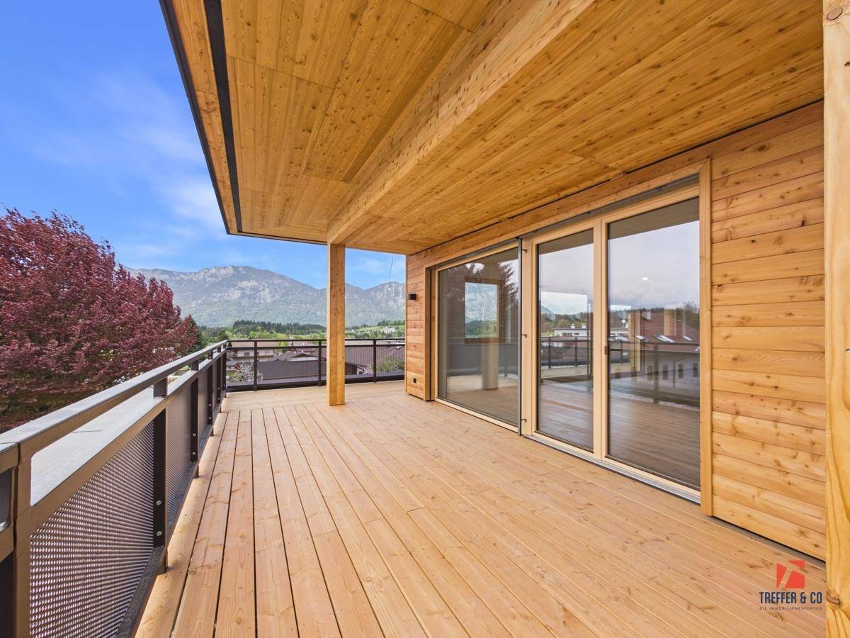 Breiter Holzbalkon mit Metallgeländer und Panoramablick auf die Berge und das Tal.