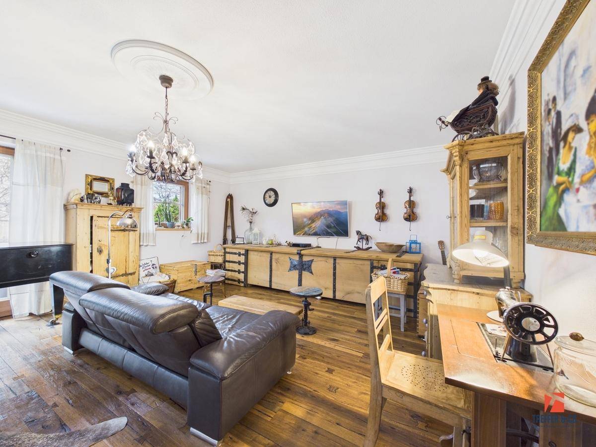 Gemütliches Wohnzimmer im Landhausstil mit Holzboden, Kronleuchter und traditionellen Holzmöbeln.