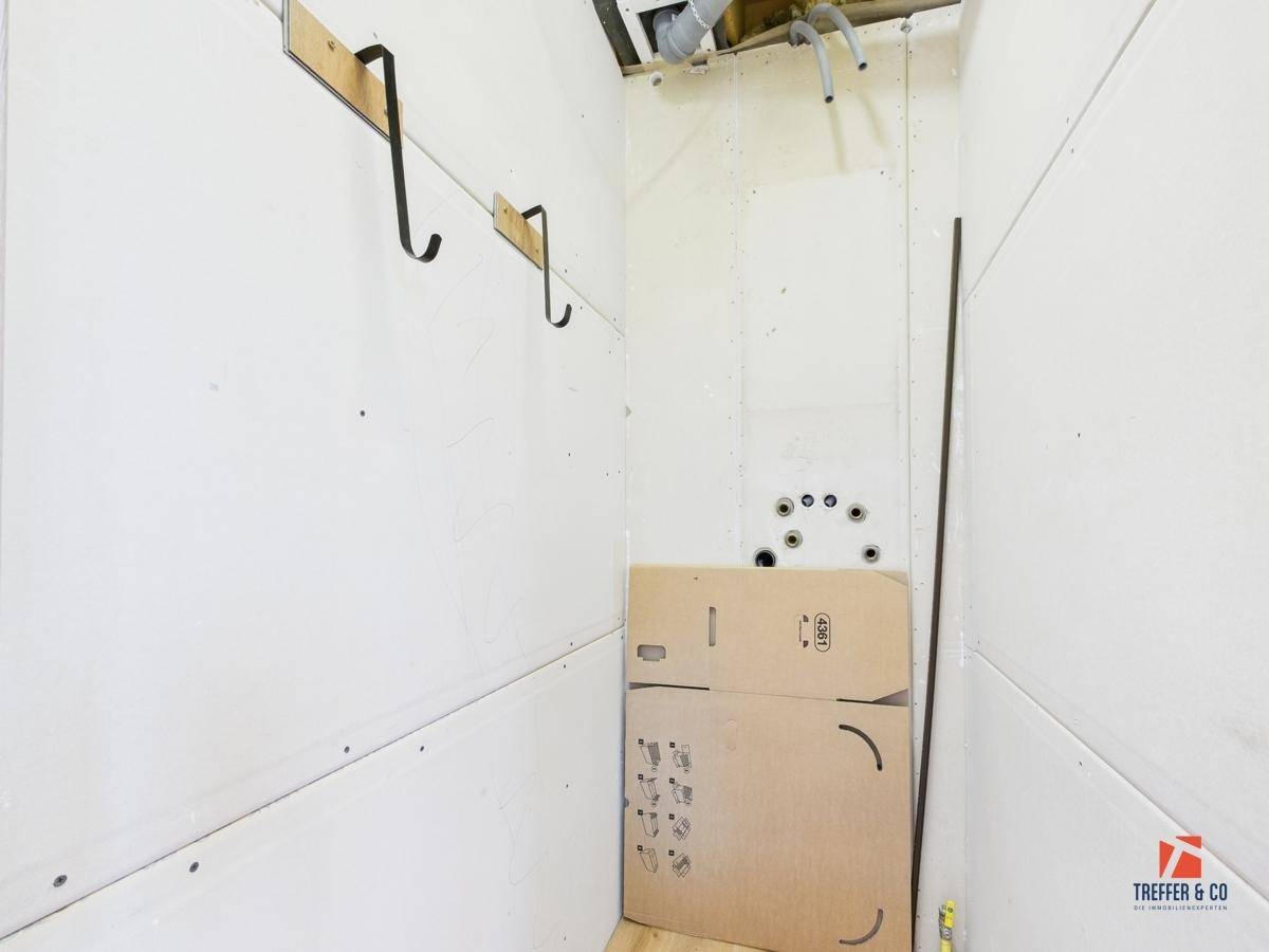 Unfertiger Hauswirtschaftsraum mit sichtbaren Leitungen und Trockenbauwänden.