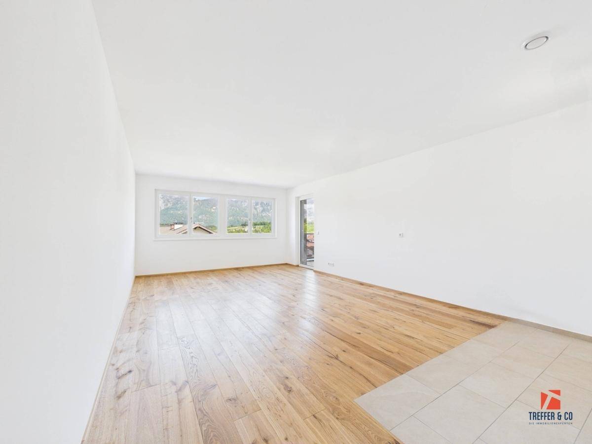 Geräumiger, leerer Raum mit Holzboden, Fliesenbereich und Zugang zu einem Balkon mit Bergblick.