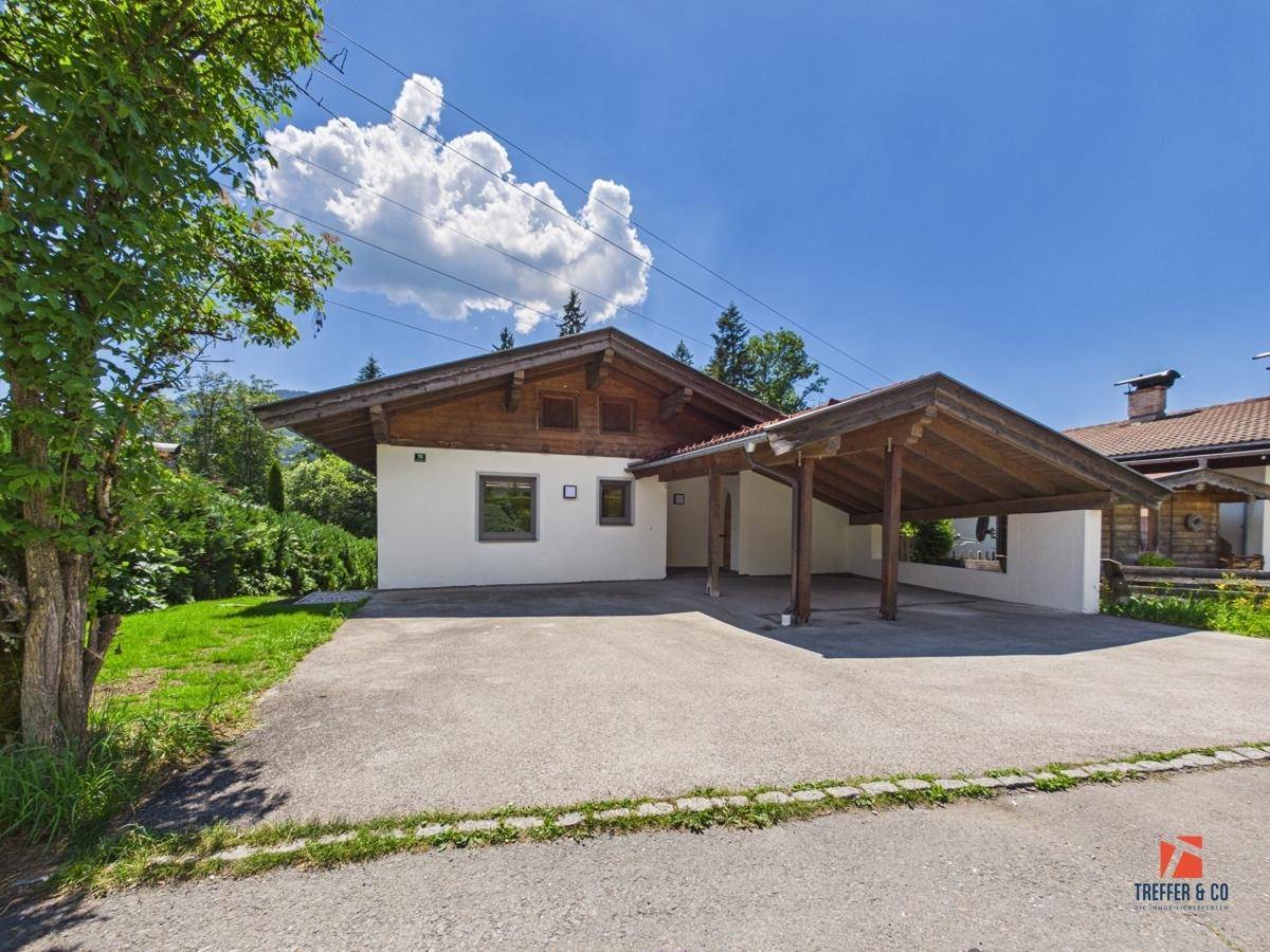 Traditionelles Chalet mit weißer Fassade, Holzelementen und einem praktischen Carport.