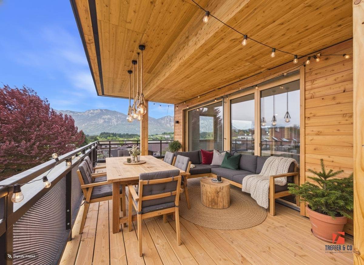 Großer Holzbalkon mit Essbereich, Lounge-Möbeln und malerischem Bergblick.