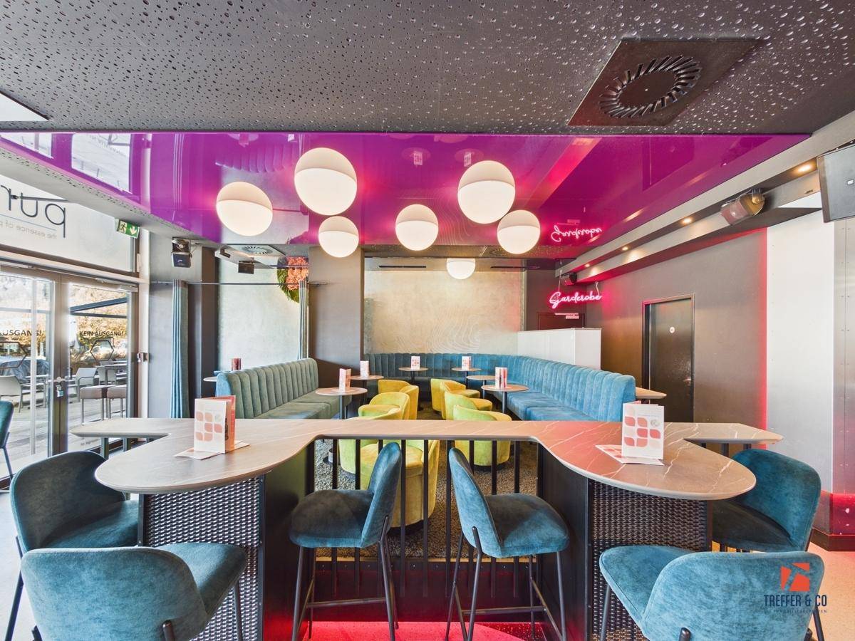 Heller Loungebereich mit bequemen Sitzbänken, hohen Tischen und einem modernen Ambiente.