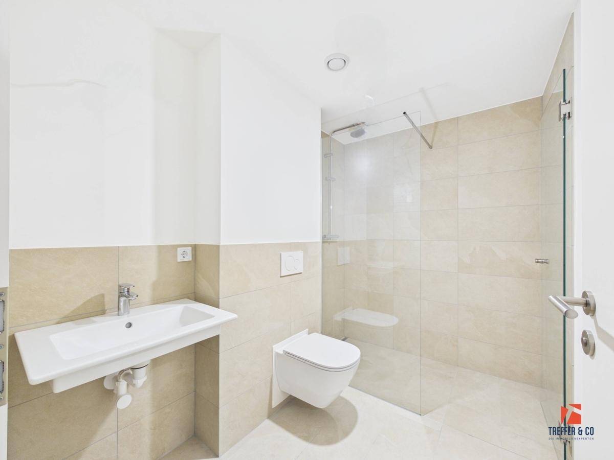 Helles Badezimmer mit modernem Design, ebenerdiger Dusche und wandhängendem WC.