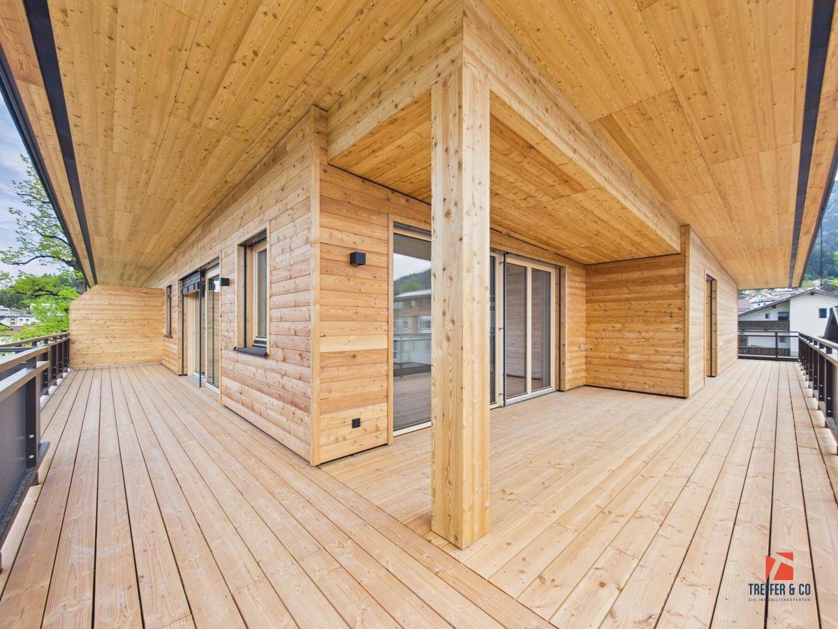 Großer Holzbalkon mit Holzverkleidung und Blick auf die umliegende Berglandschaft.