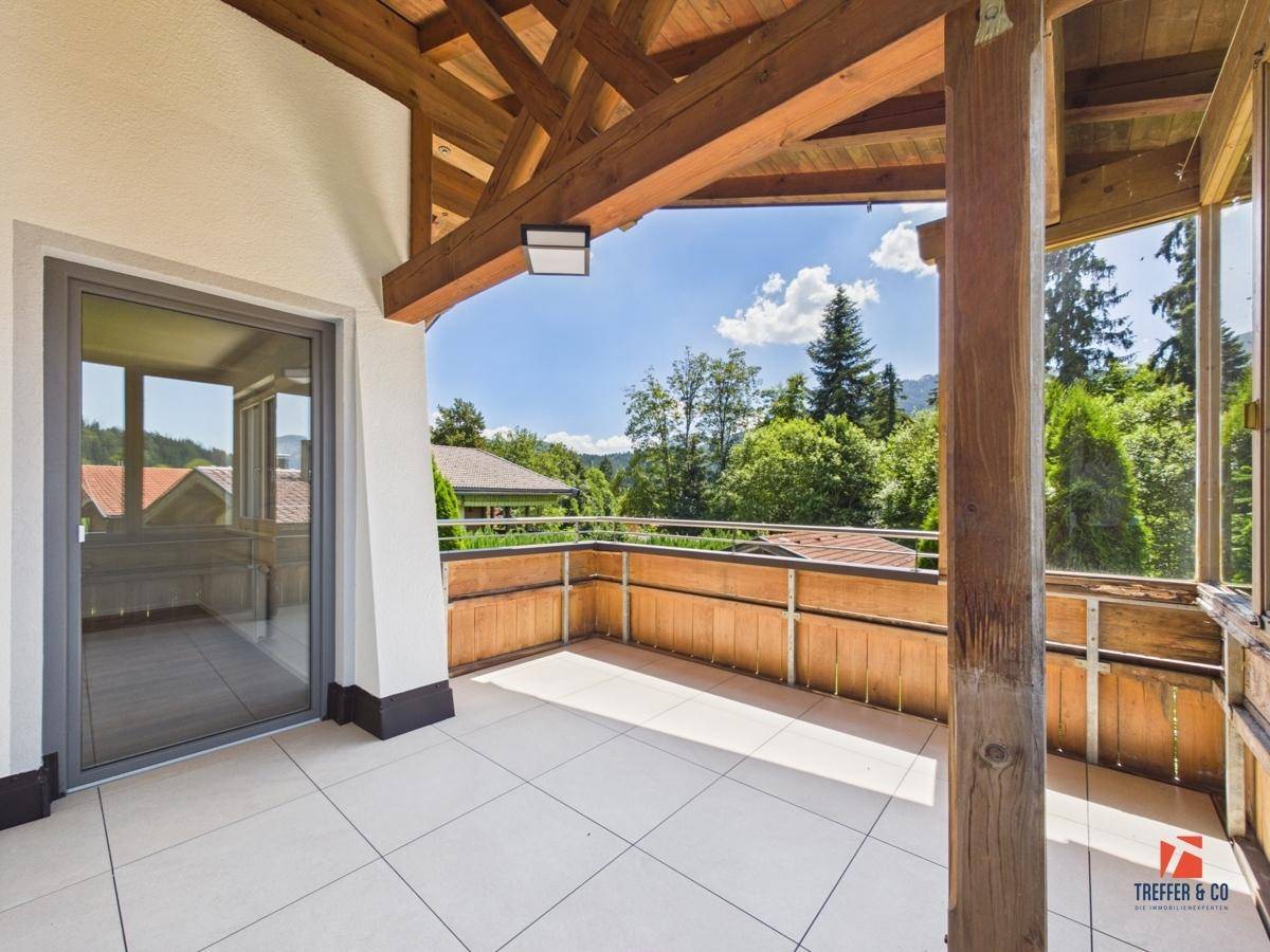 Geräumiger Balkon mit Fliesenboden, Holzbalken und weitem Blick auf die Natur.