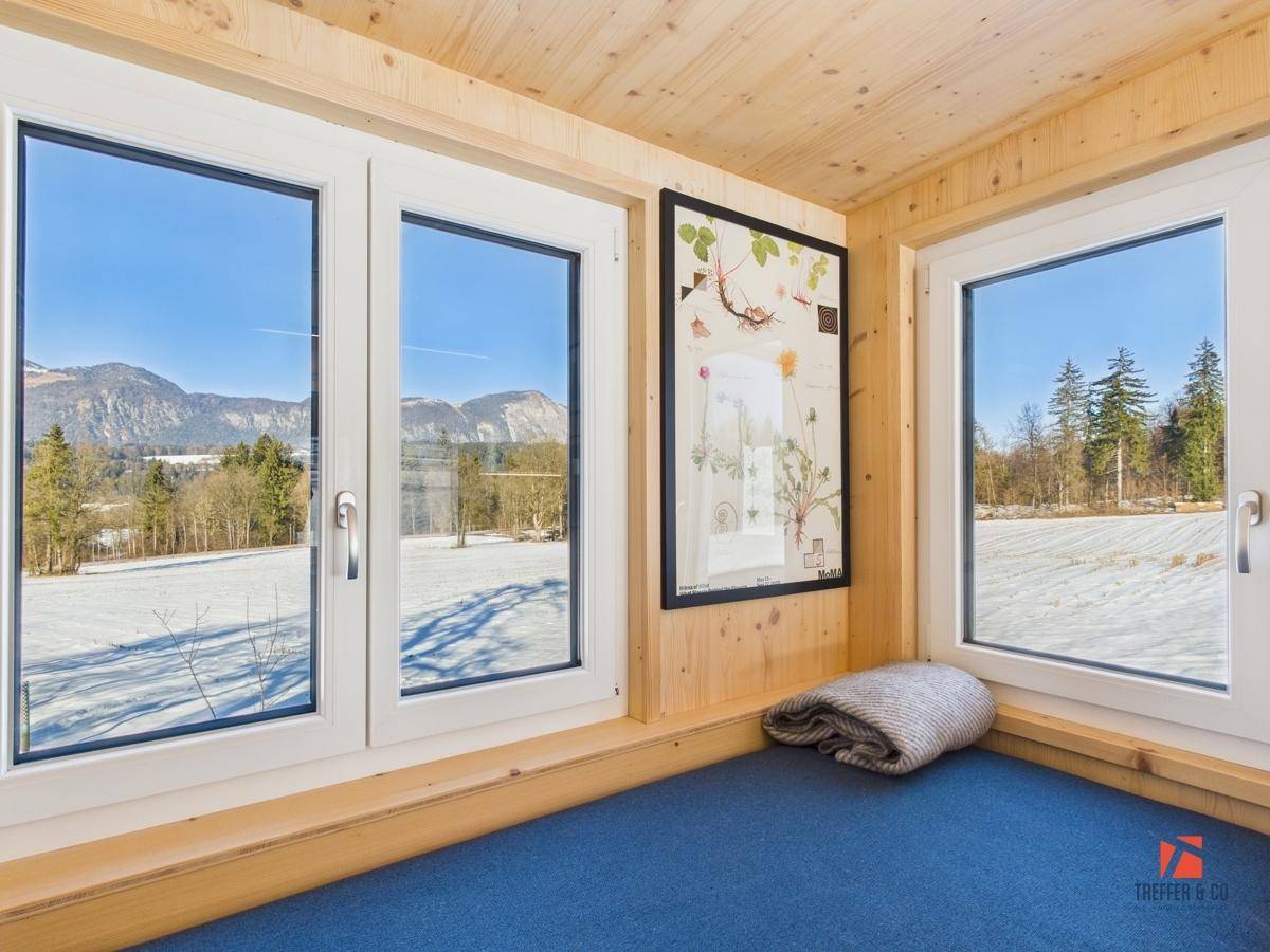 Fenster im Schlafzimmer mit weitem Blick auf die verschneite Berglandschaft und viel Tageslicht.