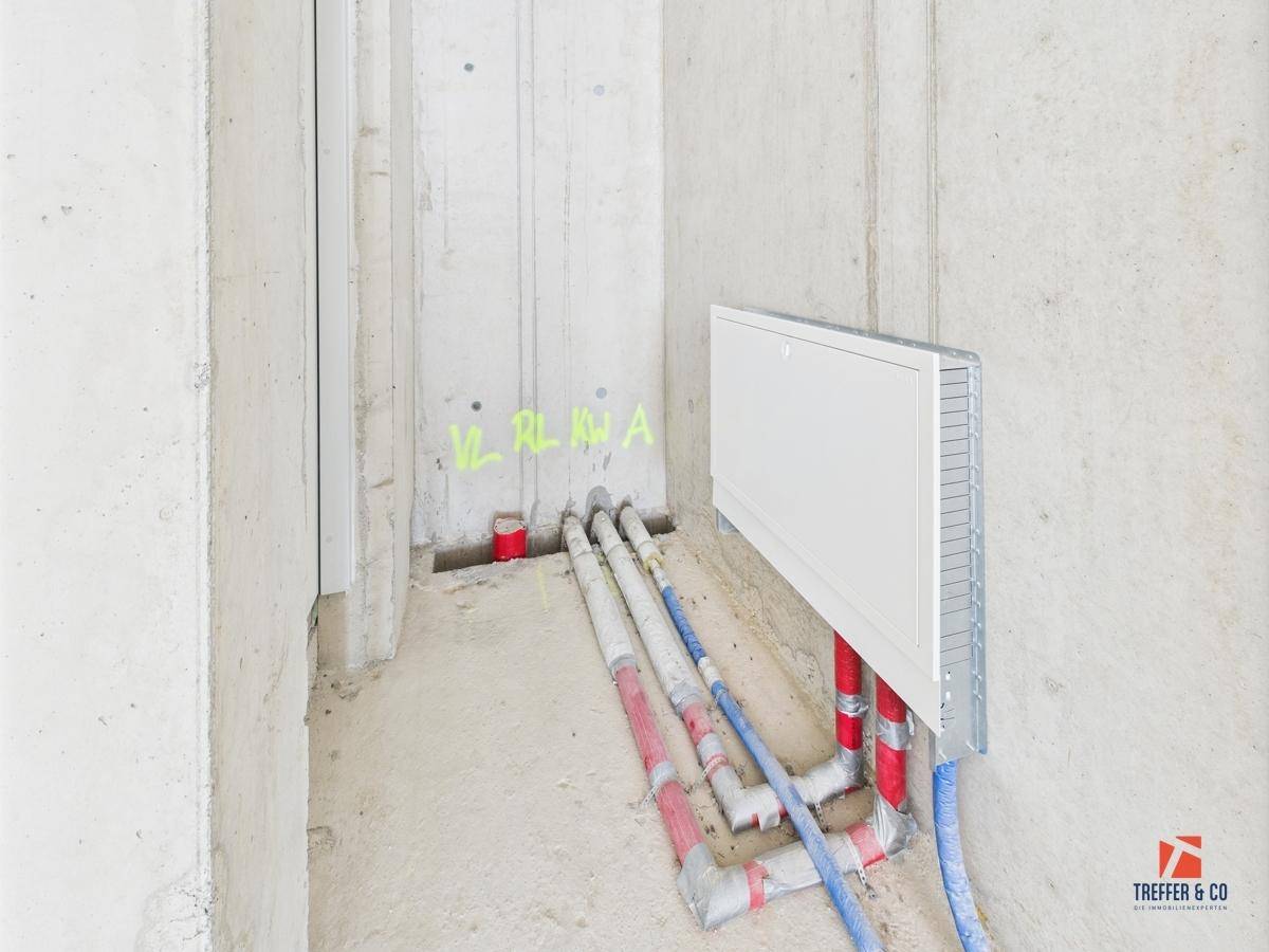 Detailansicht eines Versorgungsbereichs im Rohbau mit sichtbaren Leitungen und Installationen.