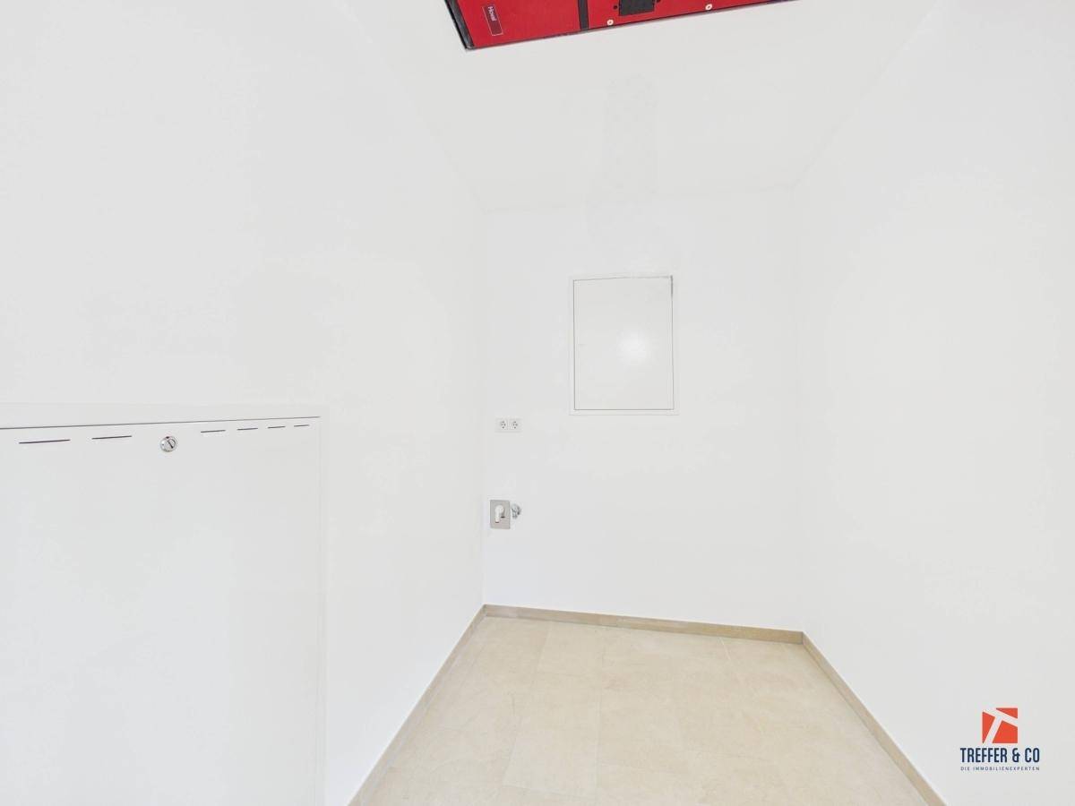 Leerer Raum mit Fliesenboden und Anschlüssen, ideal als Abstell- oder Hauswirtschaftsraum.