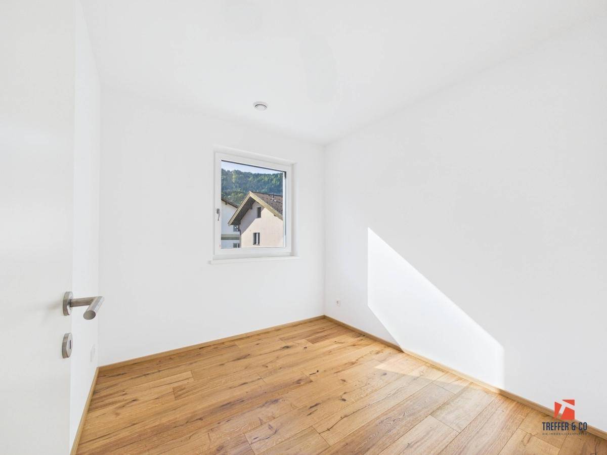 Helles Zimmer mit Holzboden und Fensterblick auf die umliegende Landschaft.