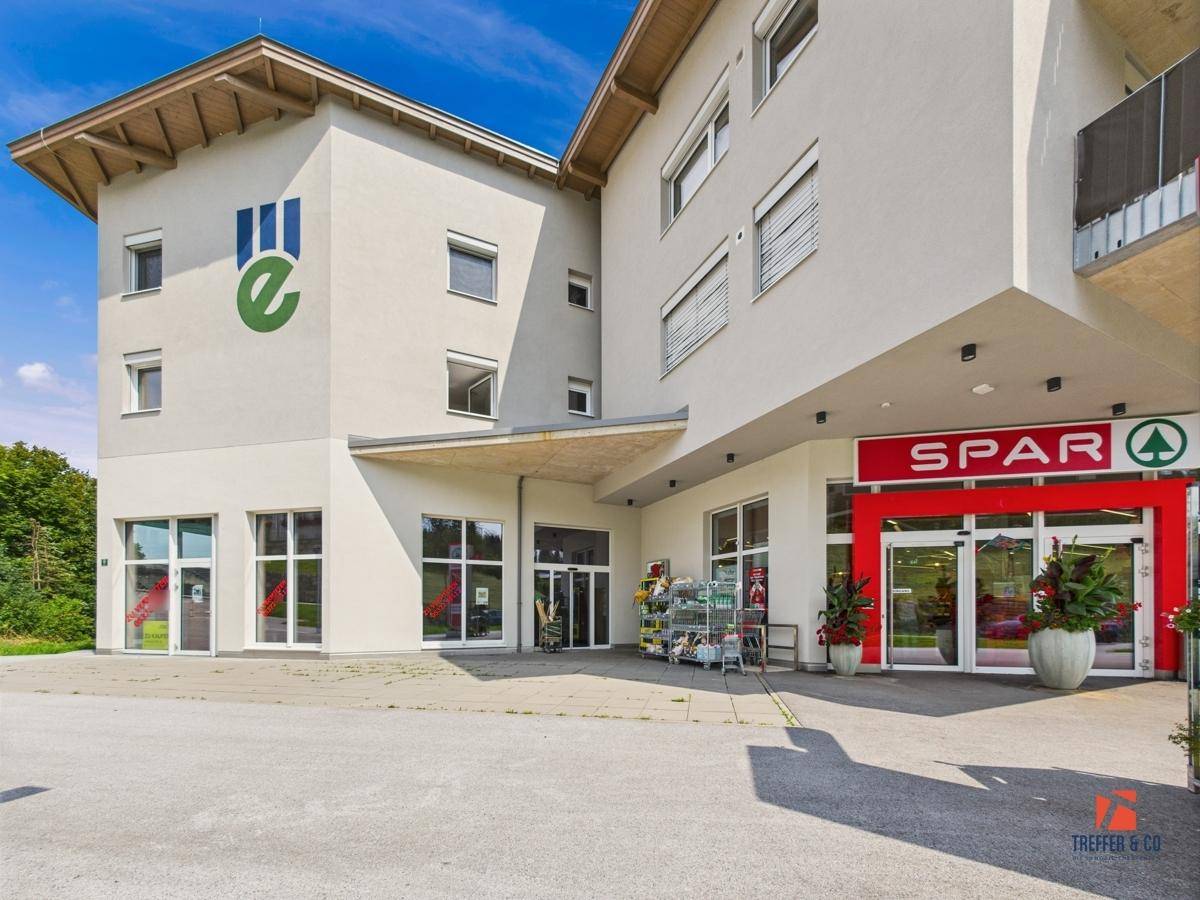 Ansicht des modernen Geschäftsgebäudes mit großen Schaufenstern und dem Eingangsbereich eines Supermarktes.