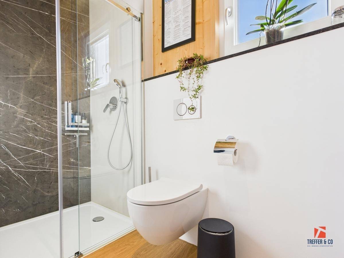 Modernes Badezimmer mit begehbarer Dusche, wandhängendem WC und stilvollen Fliesen.